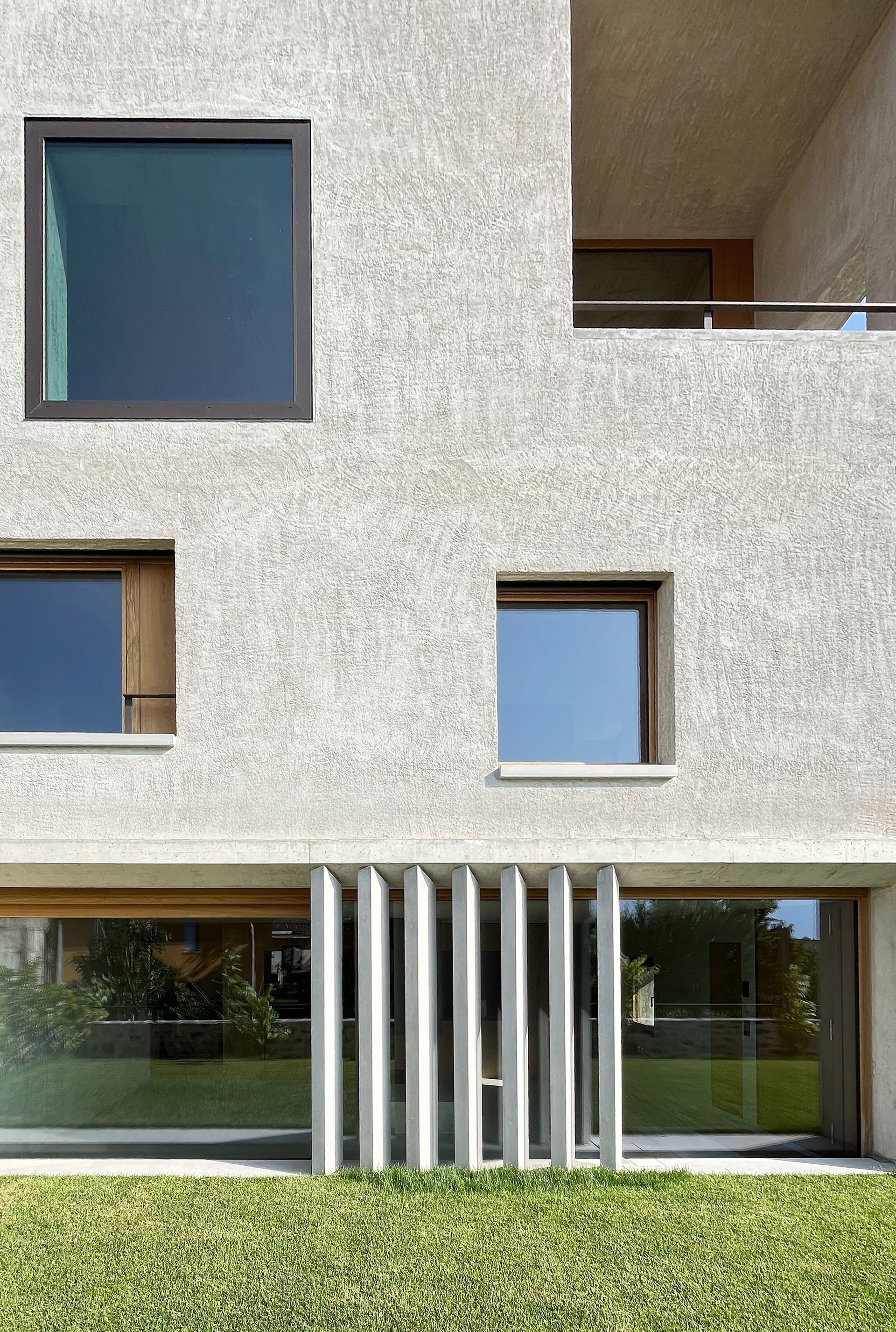 Facciata di un edificio moderno con finestre quadrate e un balcone coperto.