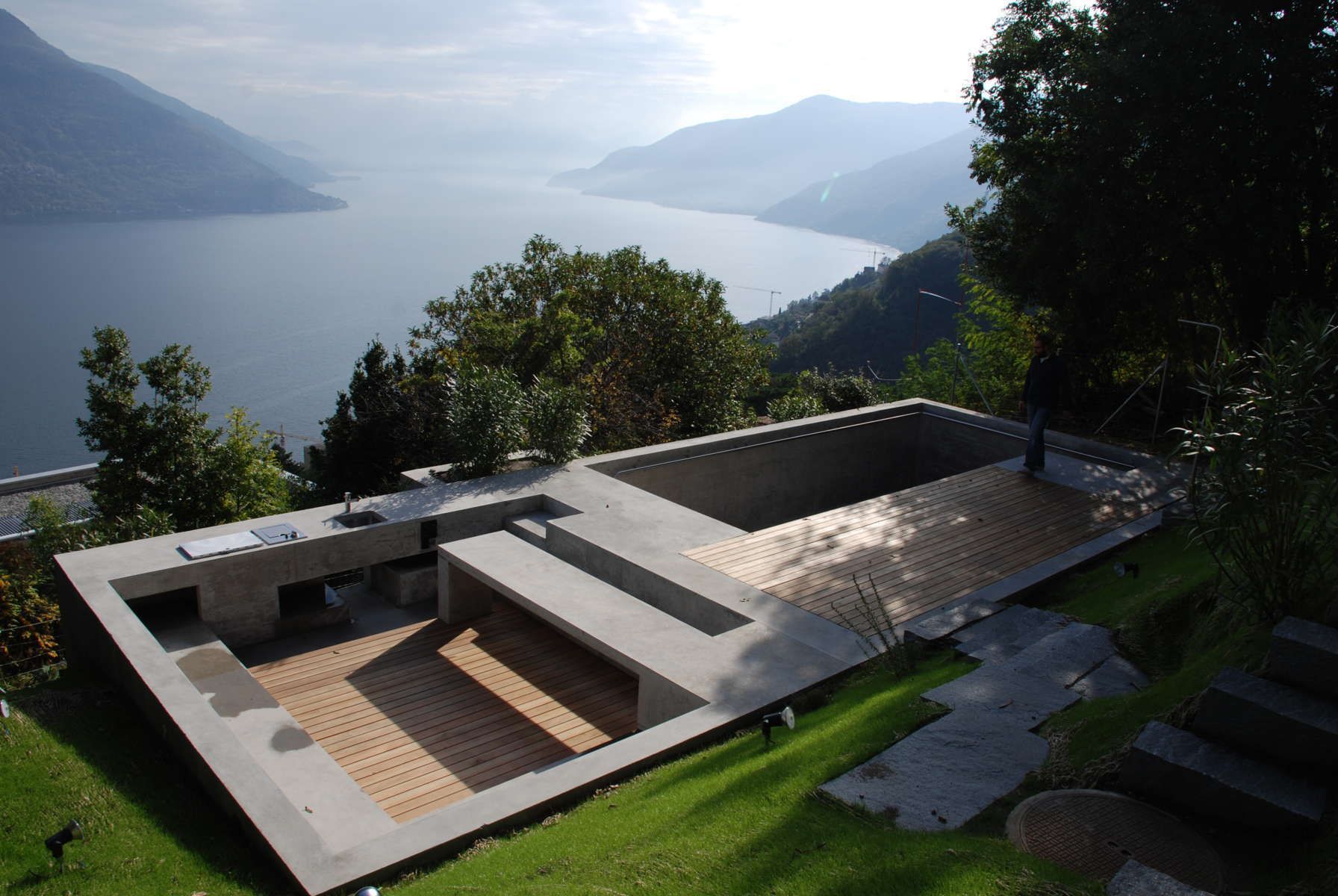 Piscina in cemento con terrazza in legno con vista sul lago e sulle montagne.