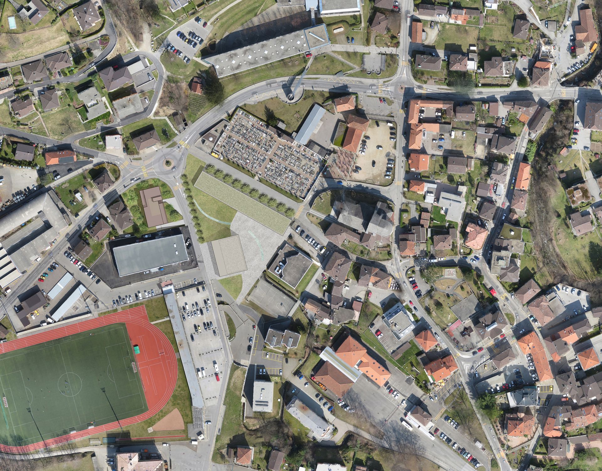 Vista aerea di una città con edifici, strade, un cimitero e un campo sportivo.