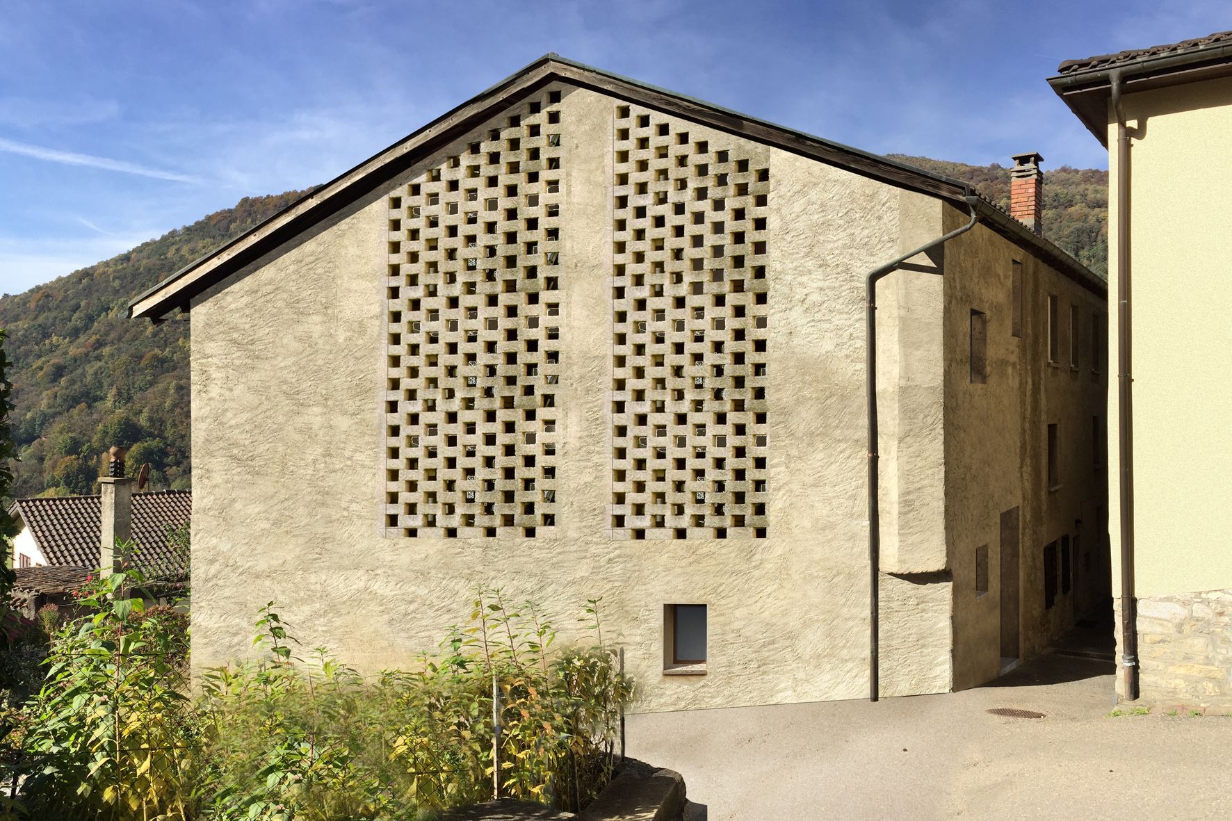 Edificio grigio con facciata decorata e tetto spiovente, in un contesto montano.