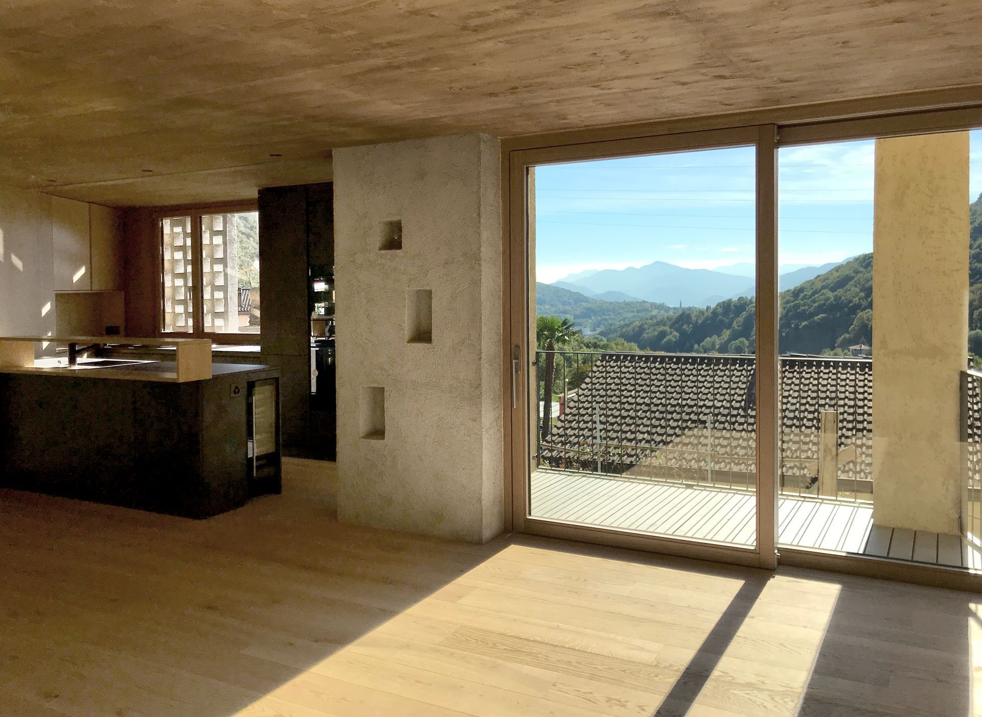 Interno di una casa moderna con vista sulle montagne attraverso porte scorrevoli in vetro.