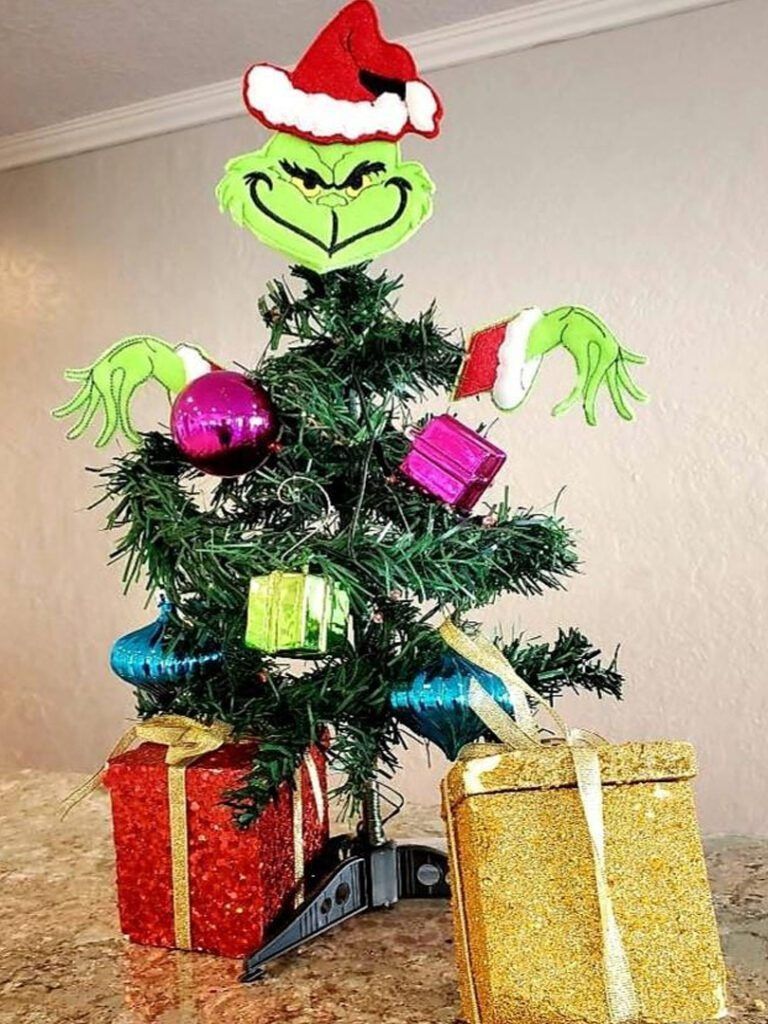 Grinch-themed Christmas tree with Grinch face topper, decorations, and gift boxes.