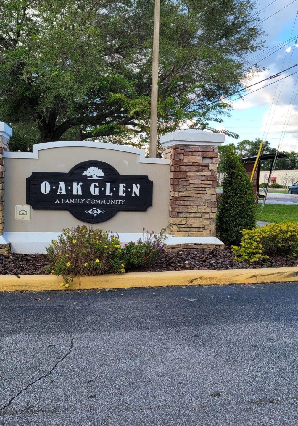 Entrance sign for Oak Glen, a family community, with black letters on a beige background; stone columns.