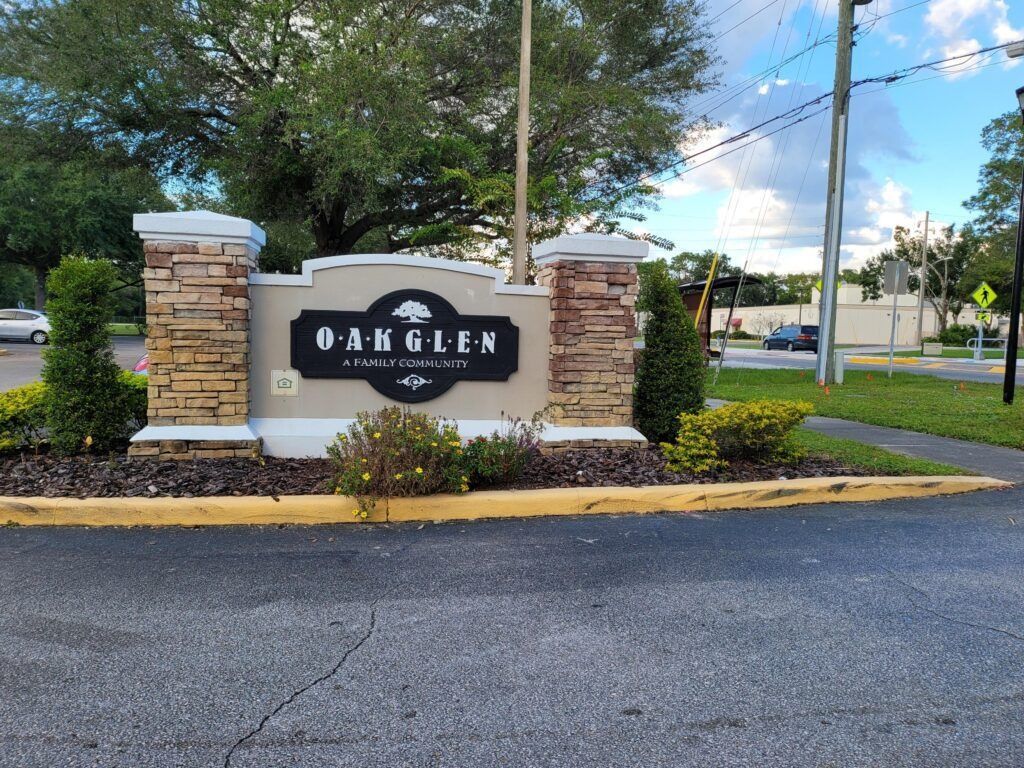 Sign for Oak Glen with stone columns, black lettering, and a tree emblem, set in an entryway.
