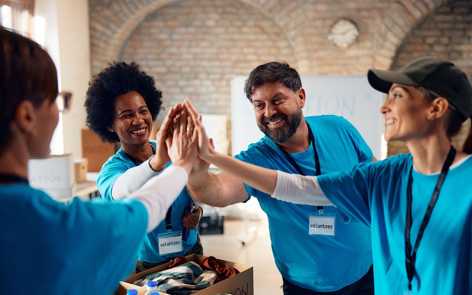 Volunteers in blue shirts high-fiving in a room, celebrating teamwork.