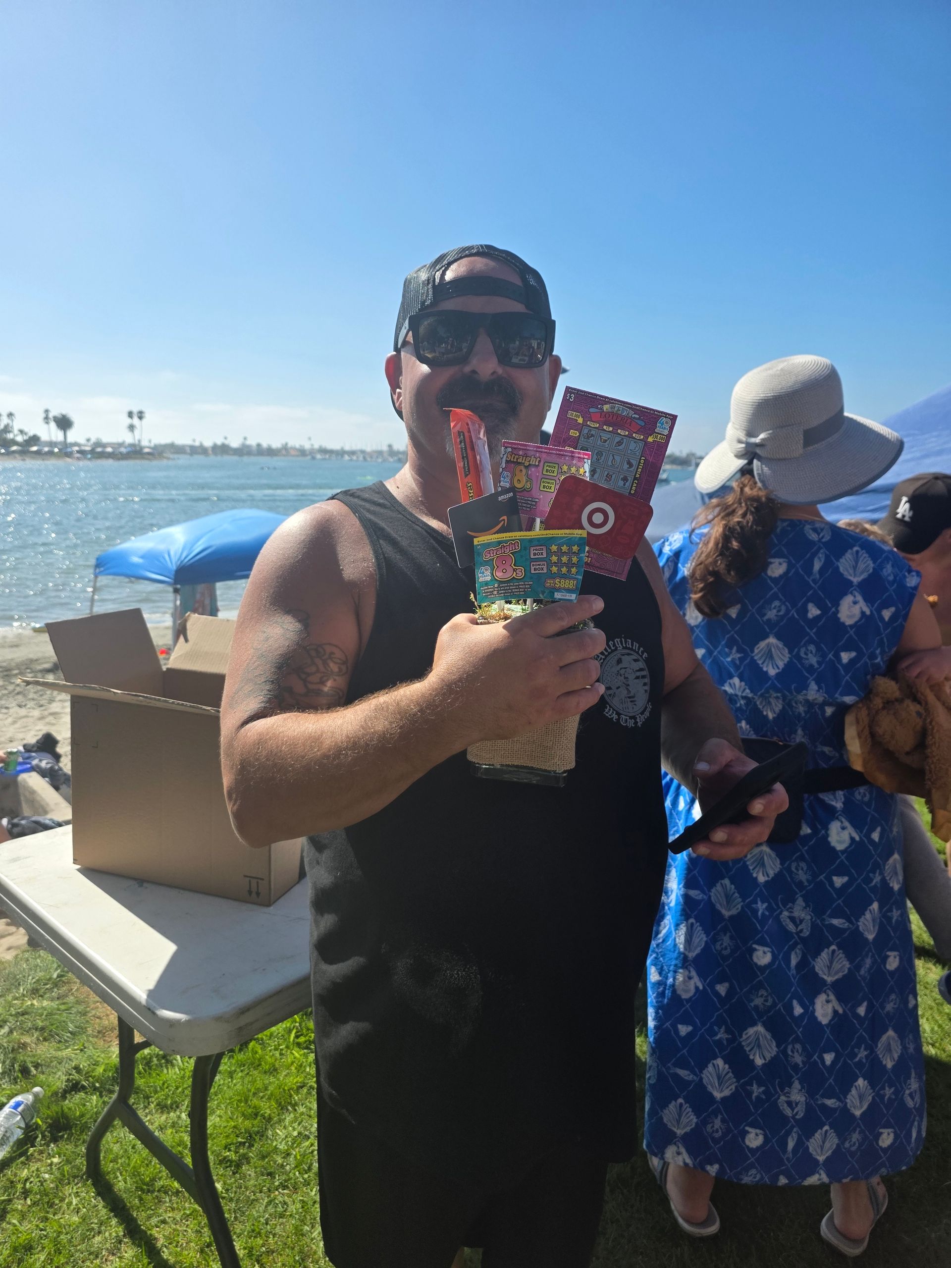 Rob, Service Advisor at Redhawk Auto Service Temecula, smiling with raffle prizes at the company picnic.