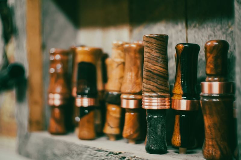 A row of wooden duck calls are lined up on a shelf.