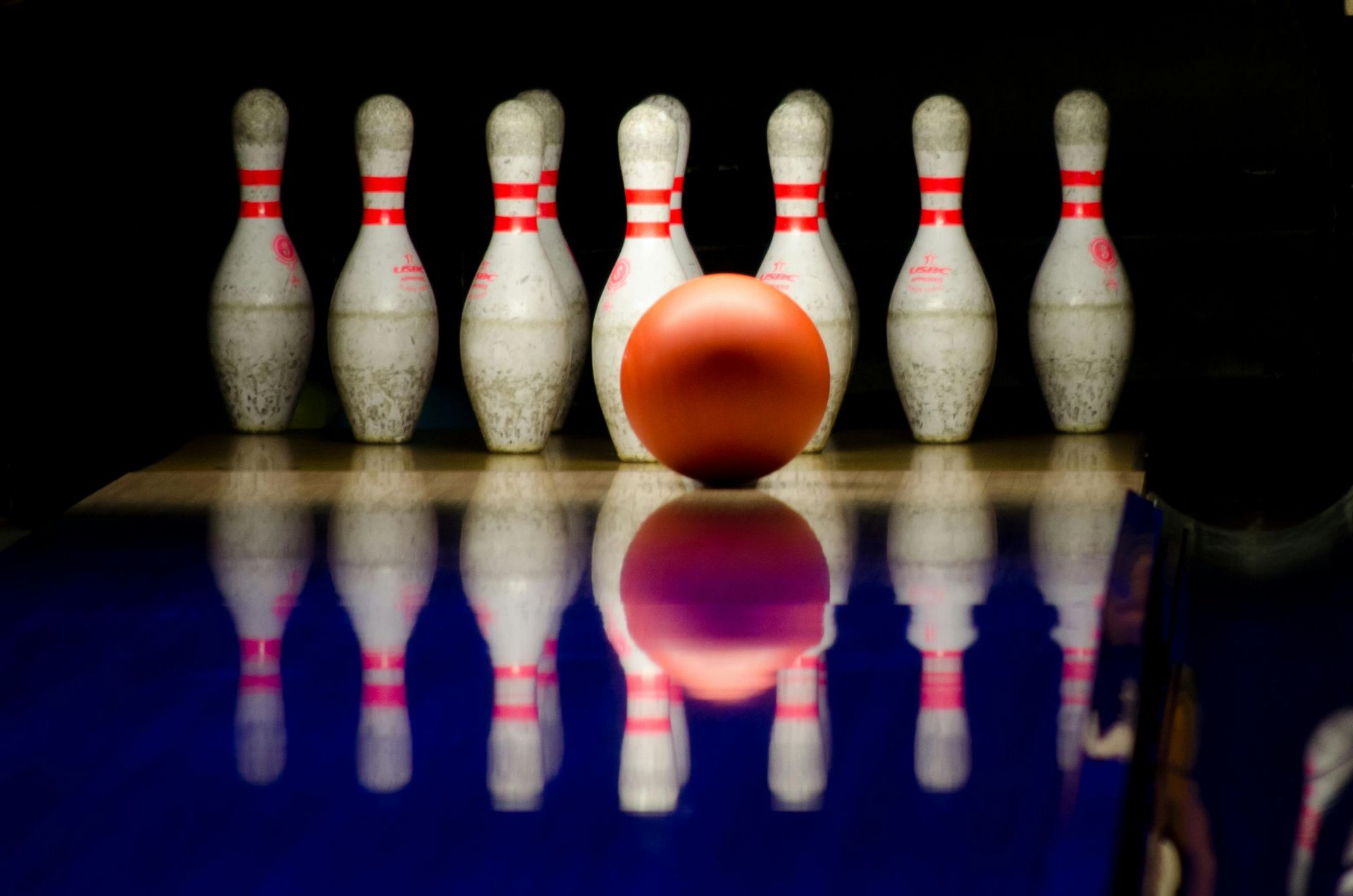 A bowling ball is sitting in front of a row of bowling pins on a bowling alley.