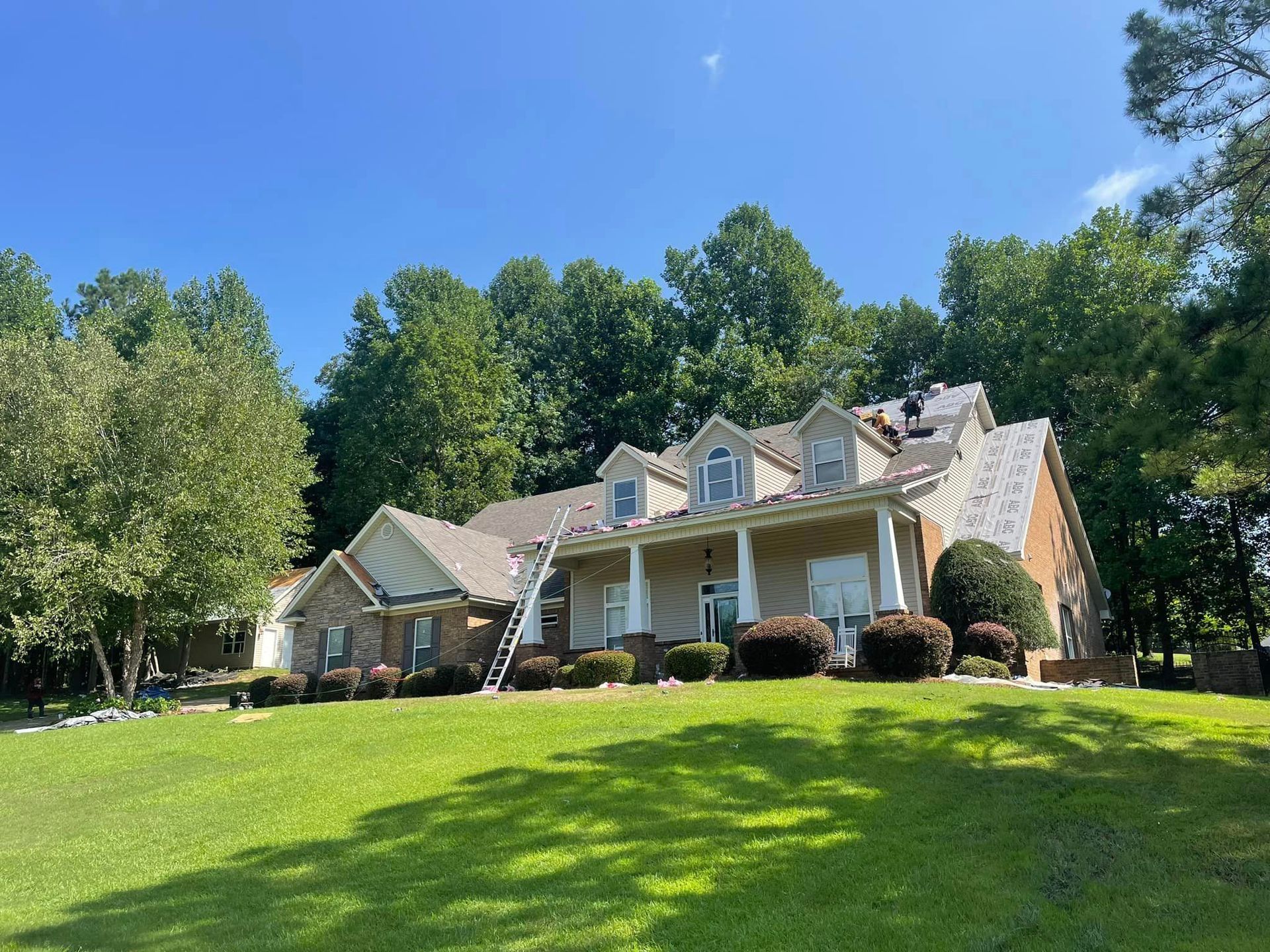 A large house is sitting on top of a lush green lawn surrounded by trees.