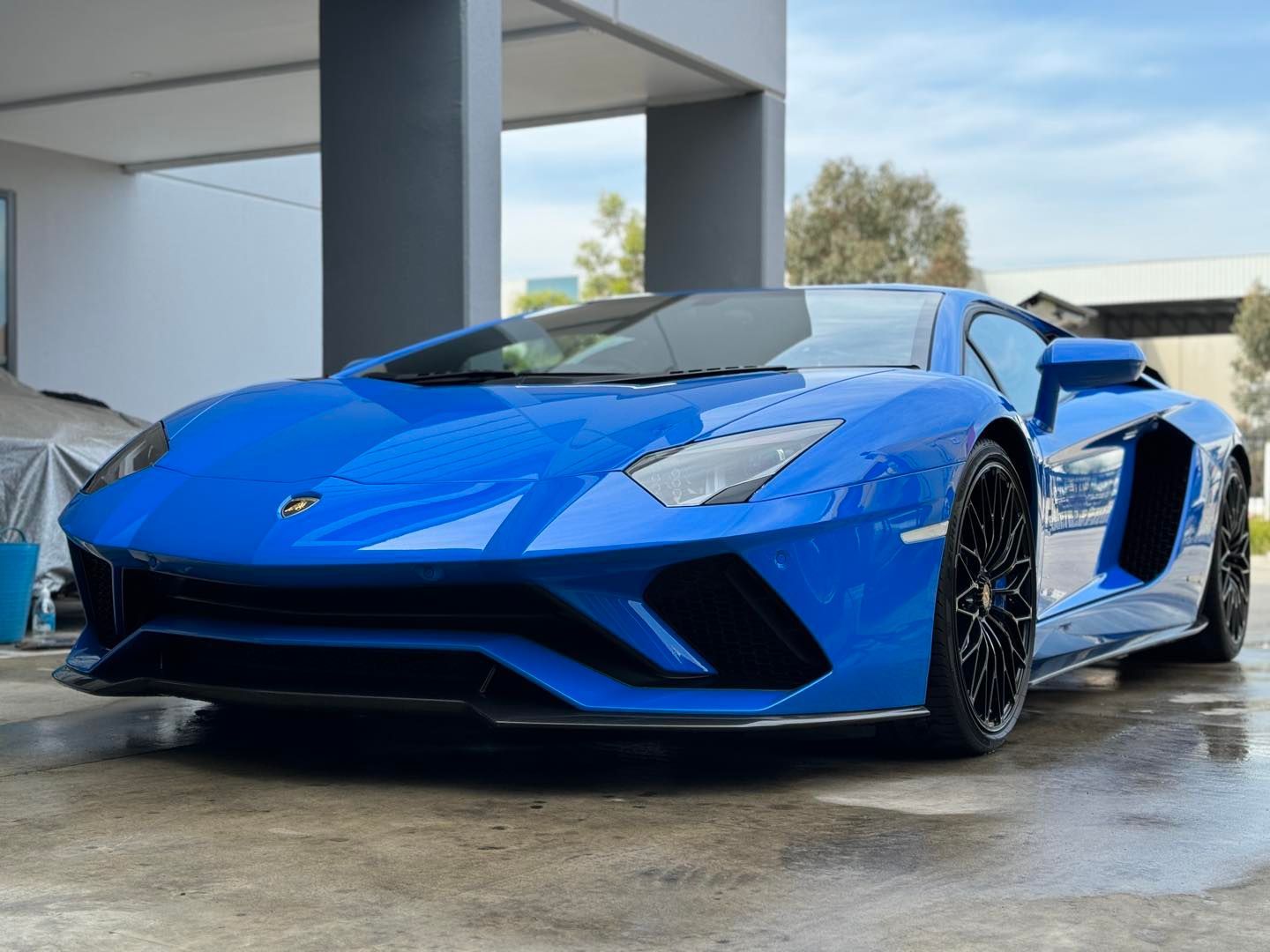 a blue lamborghini aventador is parked in front of a building