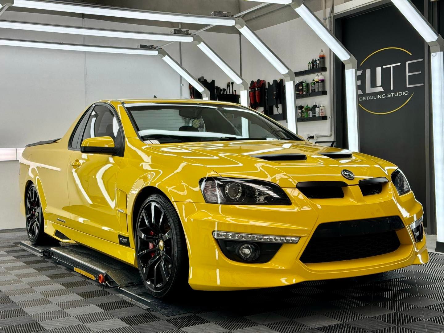 Yellow sports utility vehicle in a bright garage, with a black trim and wheels.