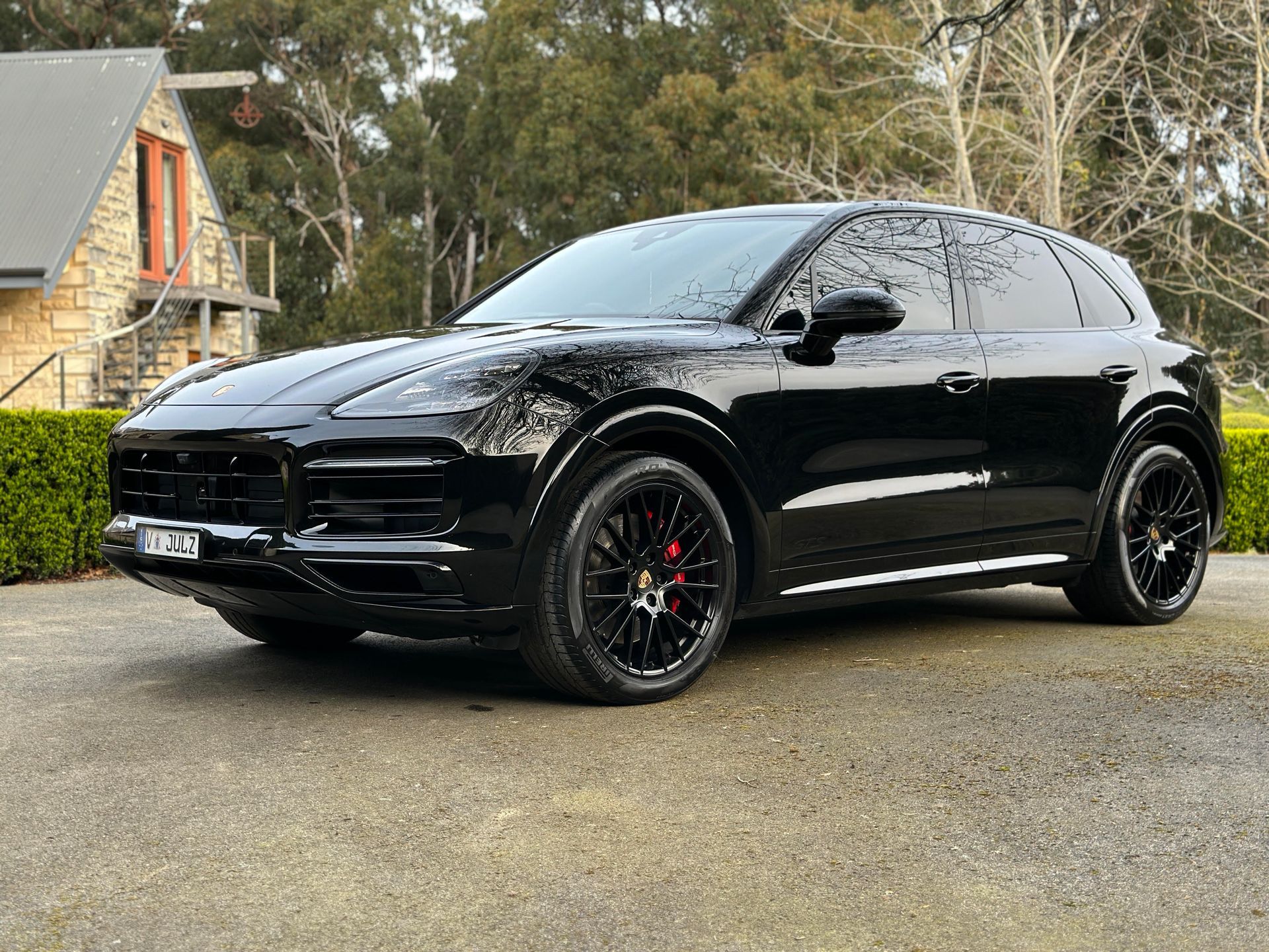 Ceramic Coating - A black Porsche Cayenne GTS is parked in front of a house