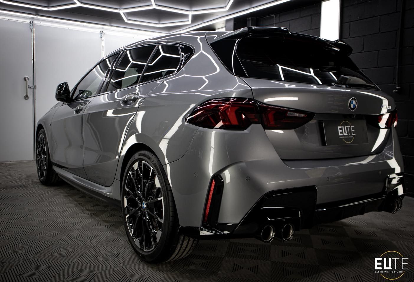 Gray BMW hatchback with black wheels and trim, angled view in a well-lit garage.