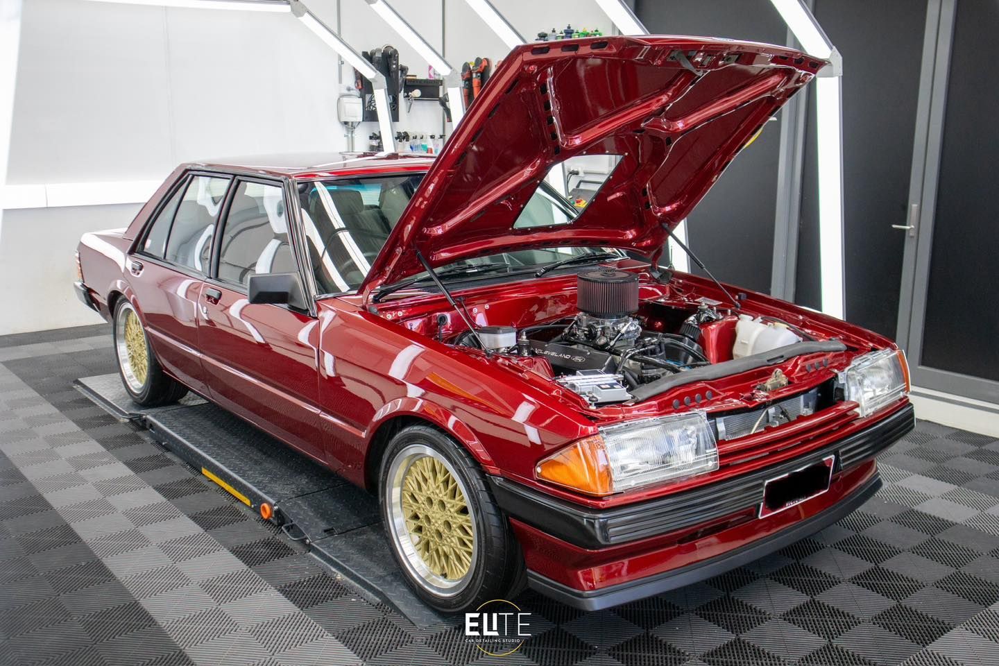 Ceramic Coating: A red car with the hood up is parked in a garage.