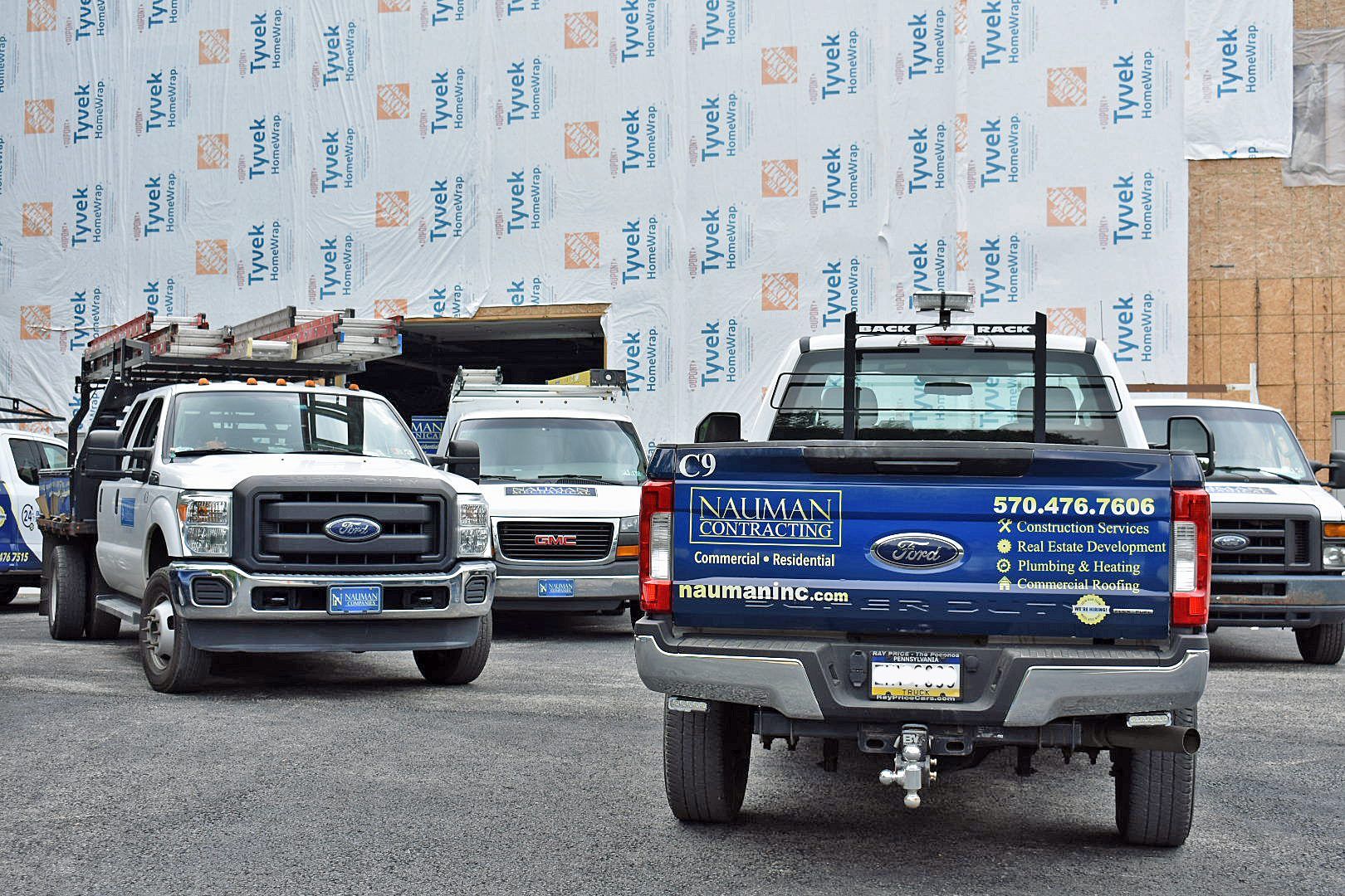 A row of Nauman inc. trucks are parked in front of a building under construction.
