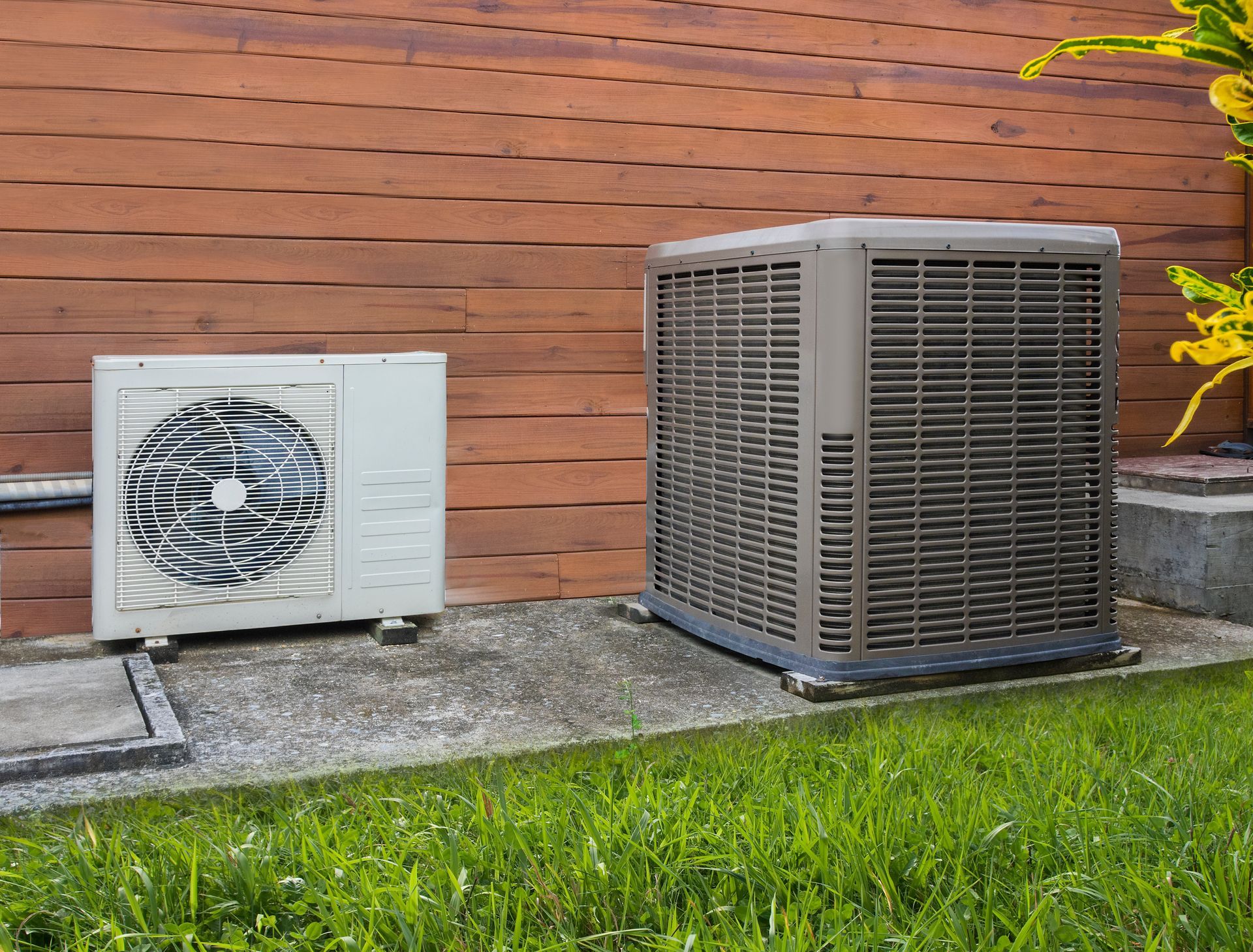 A worker from Nauman Inc. is working on an air conditioner outside of a house.