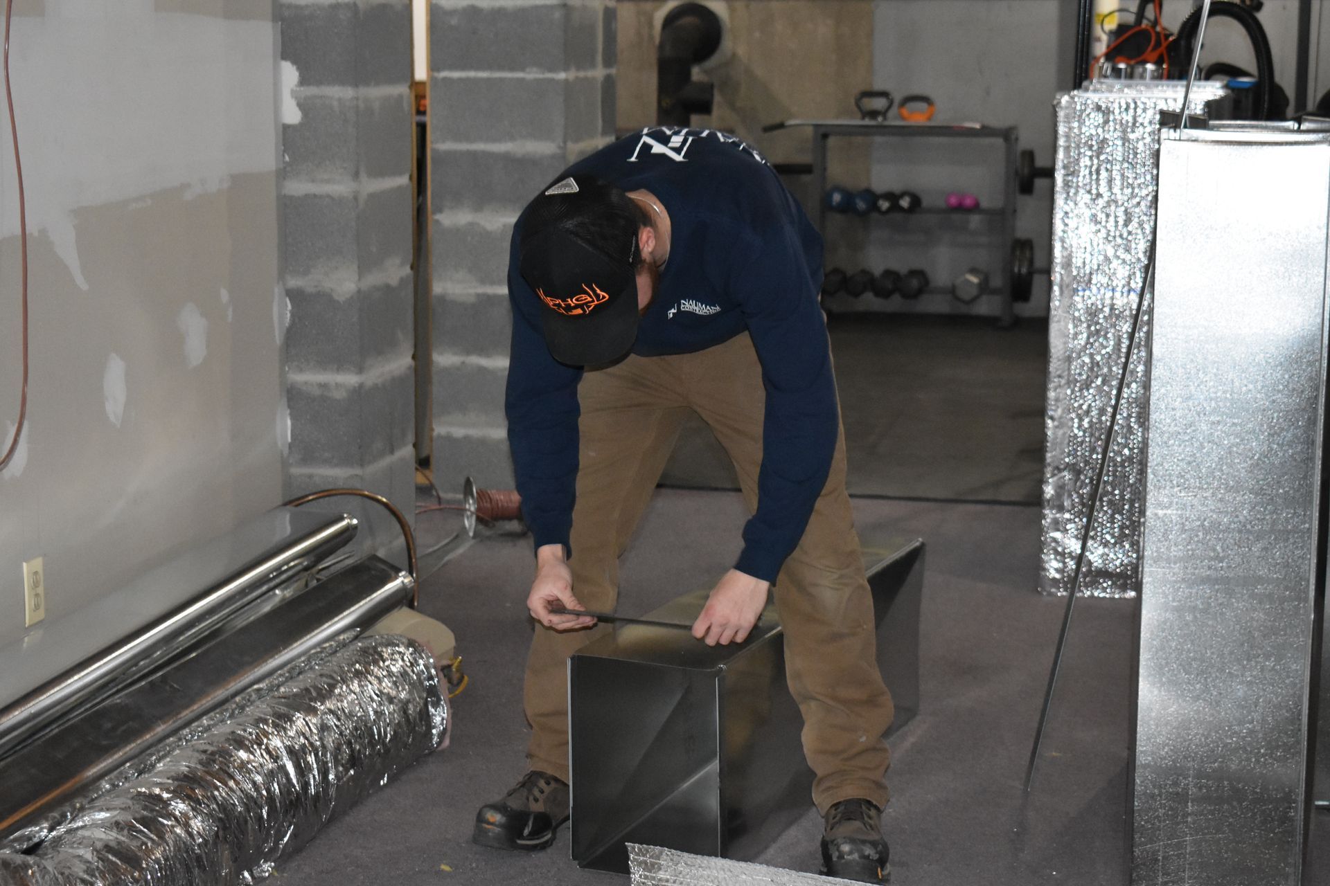 A man in a blue shirt from Nauman Inc. is working on a piece of metal