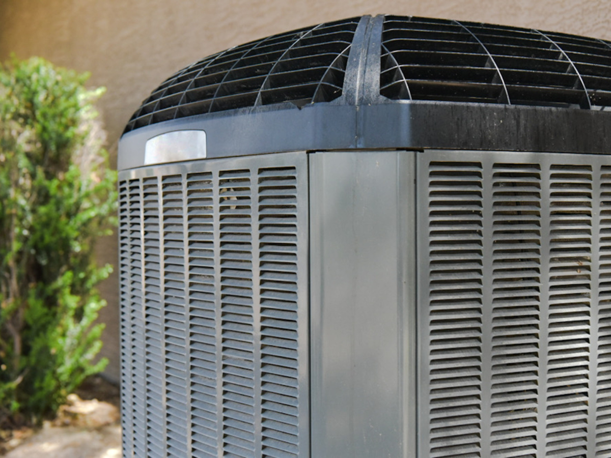 A large air conditioner is sitting outside of a building.