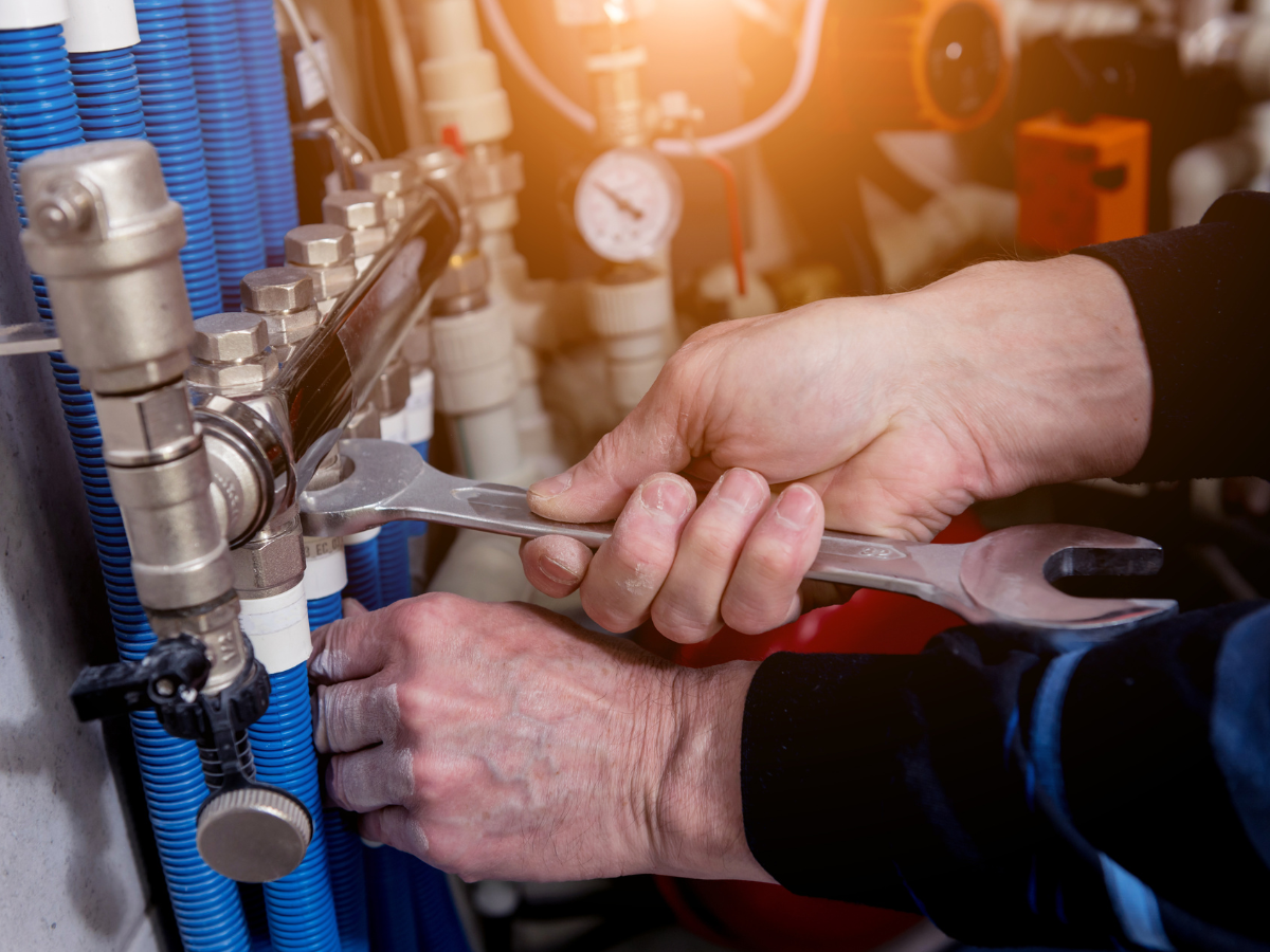 A man is fixing a pipe with a wrench.