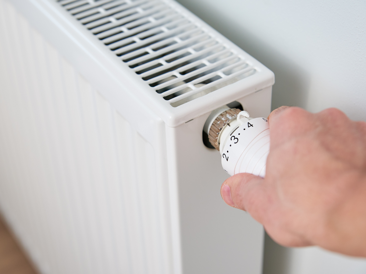 A person is adjusting a thermostat on a radiator.