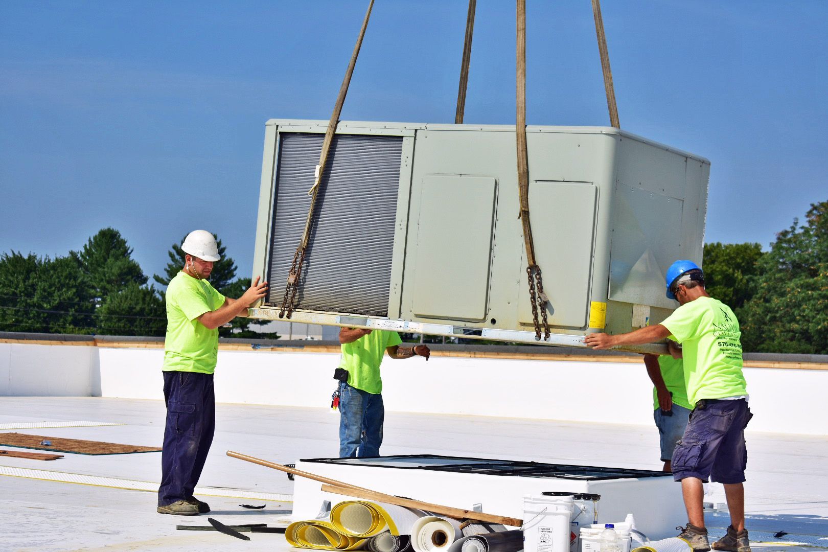 A group of Nauman Inc. workers are installing an HVAC system on top of a building.