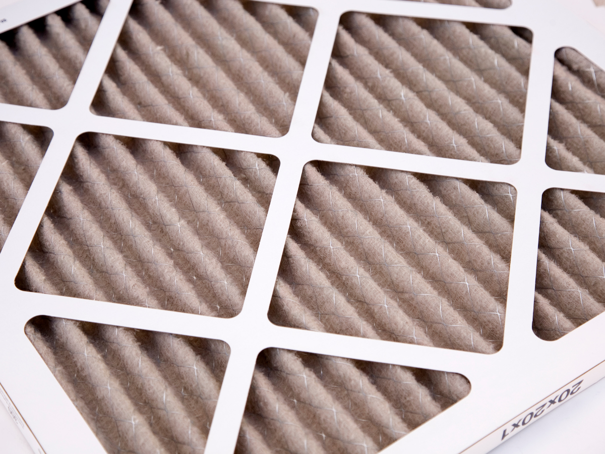 Three men from Nauman Inc. are standing next to a large air conditioner.
