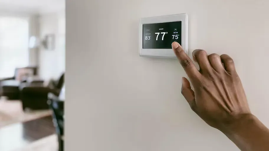 A person is adjusting a thermostat on a wall in a living room.