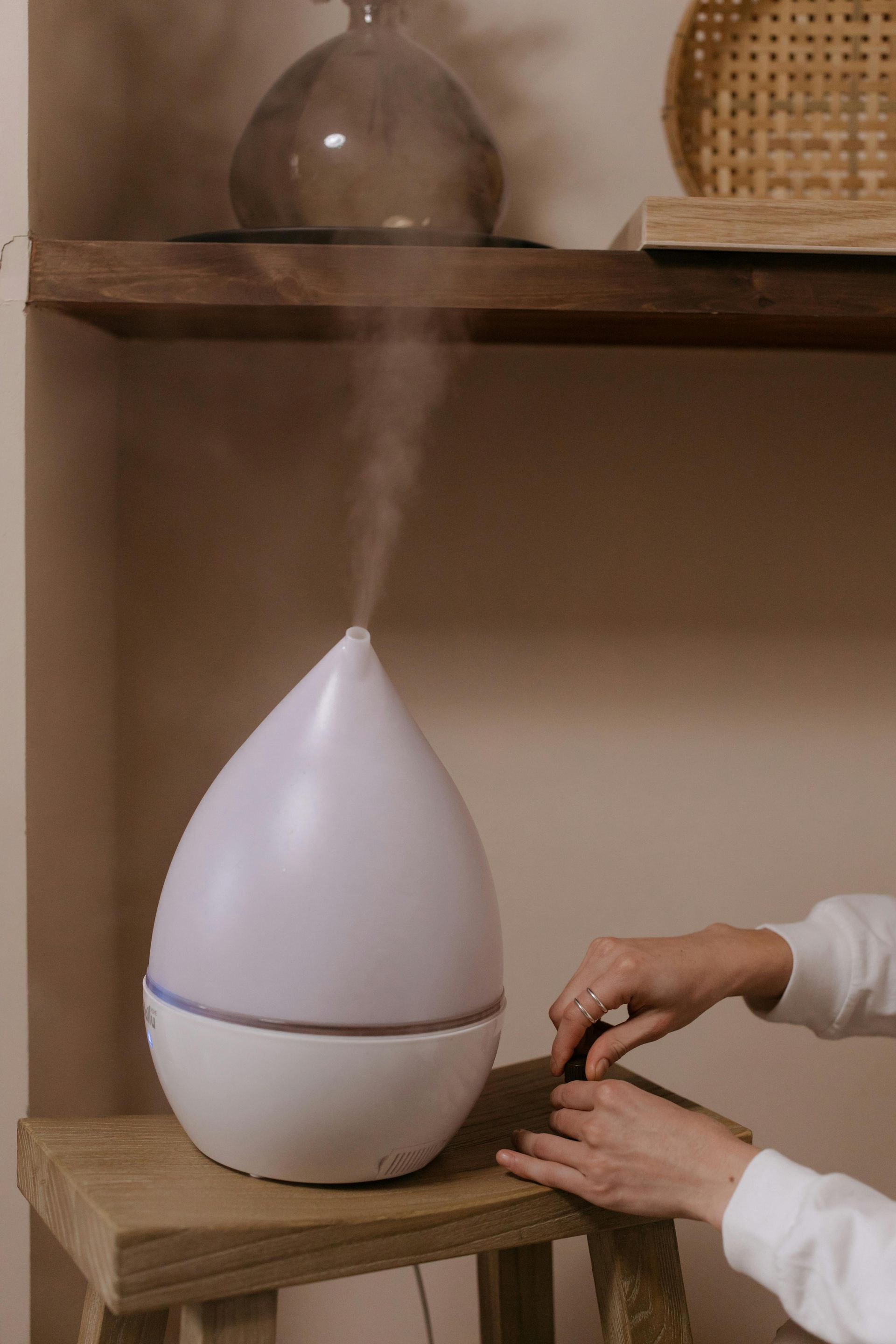 A person is sitting on a stool using an essential oil diffuser.