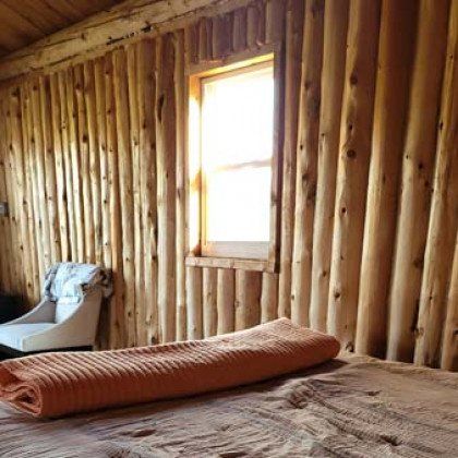 A bed with a towel on it in a room with wooden walls and a window.