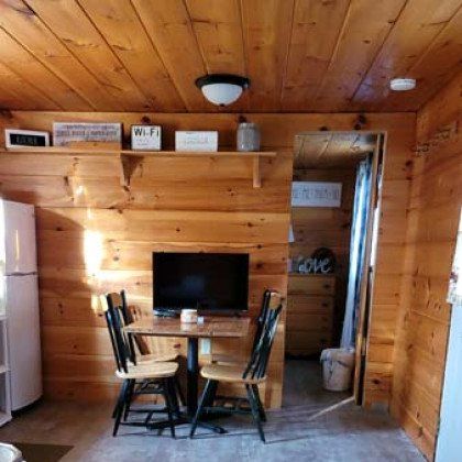 A wooden room with a table and chairs and a flat screen tv.