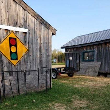 A traffic light sign is hanging on the side of a wooden building.