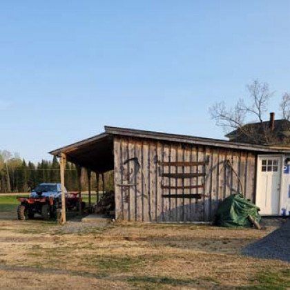 A wooden shed with a car parked in front of it.