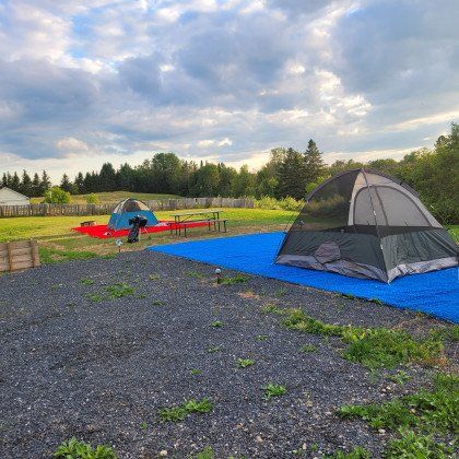 A tent is sitting on top of a blue tarp in a gravel area.
