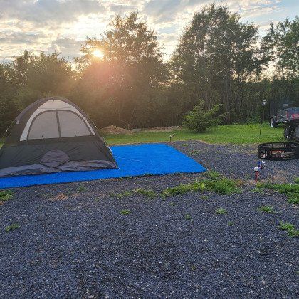 A tent is sitting on top of a blue mat in a gravel area.