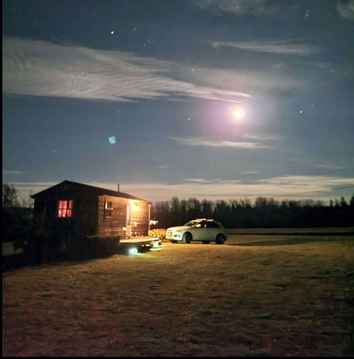 A car is parked in front of a small house at night