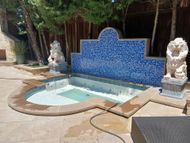 A swimming pool with a fountain and statues in the backyard.