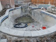 An empty swimming pool is being built in a backyard