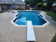 A large swimming pool with a diving board in front of it