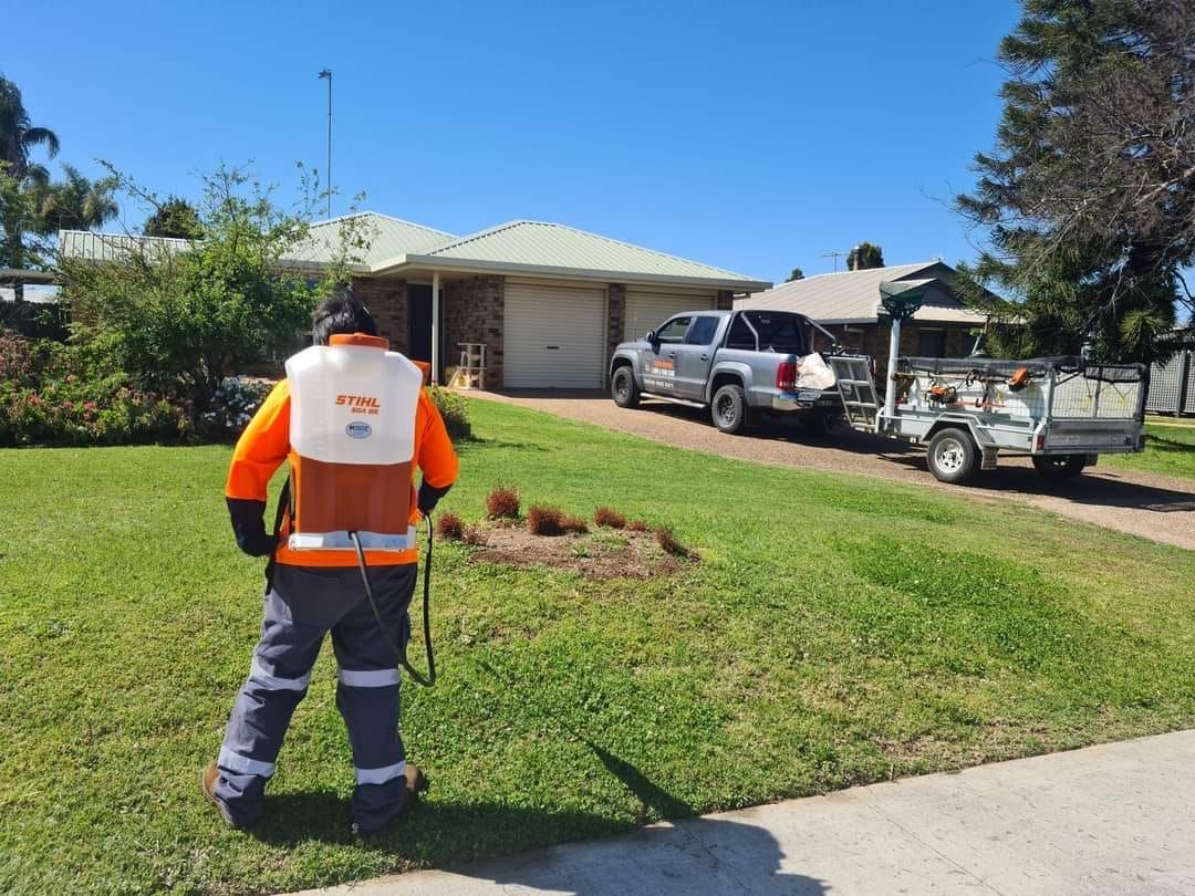 Worker in Safety Vest Stands on a Lawn Near a Utility Trucks — Toowoomba Lawn and Yard care In Highfields, QLD