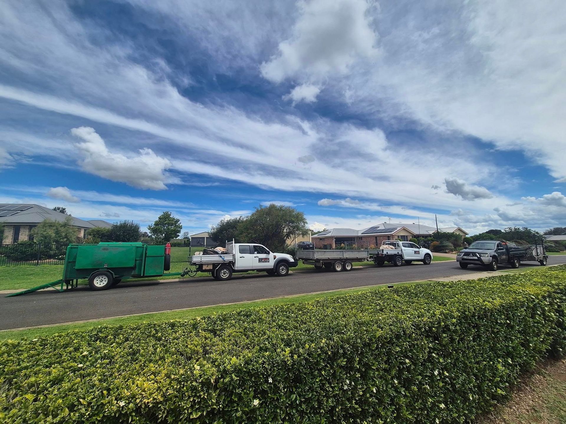 Parked Vehicles and a Green Trailer Beside a Hedge — Toowoomba Lawn and Yard care In Glenvale, QLD