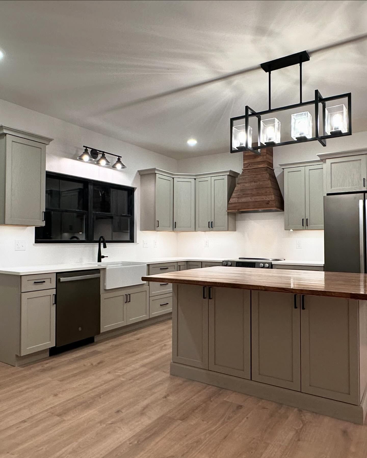 Modern kitchen with green cabinets, wood island, and black accents.