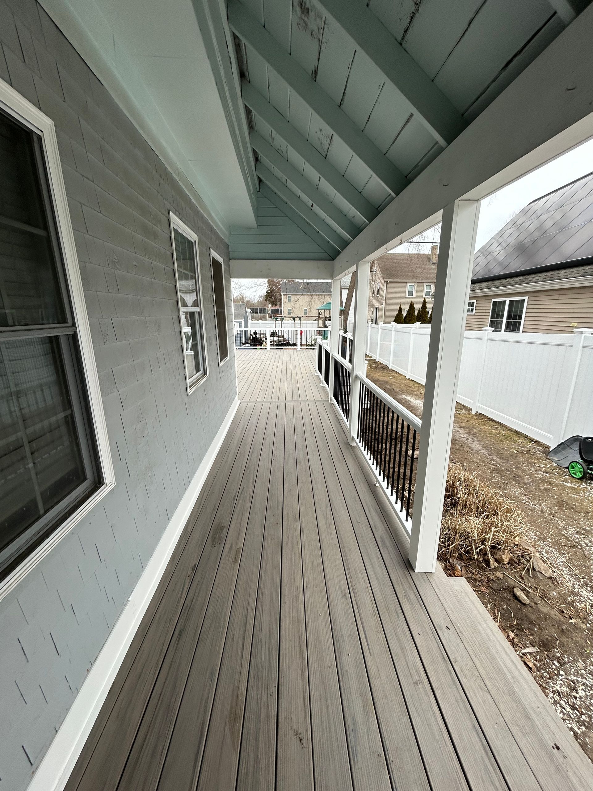 A long wooden walkway leading to a house with a white fence.