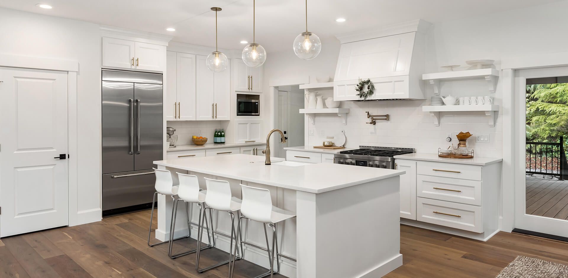 A kitchen with white cabinets , stainless steel appliances , and a large island.