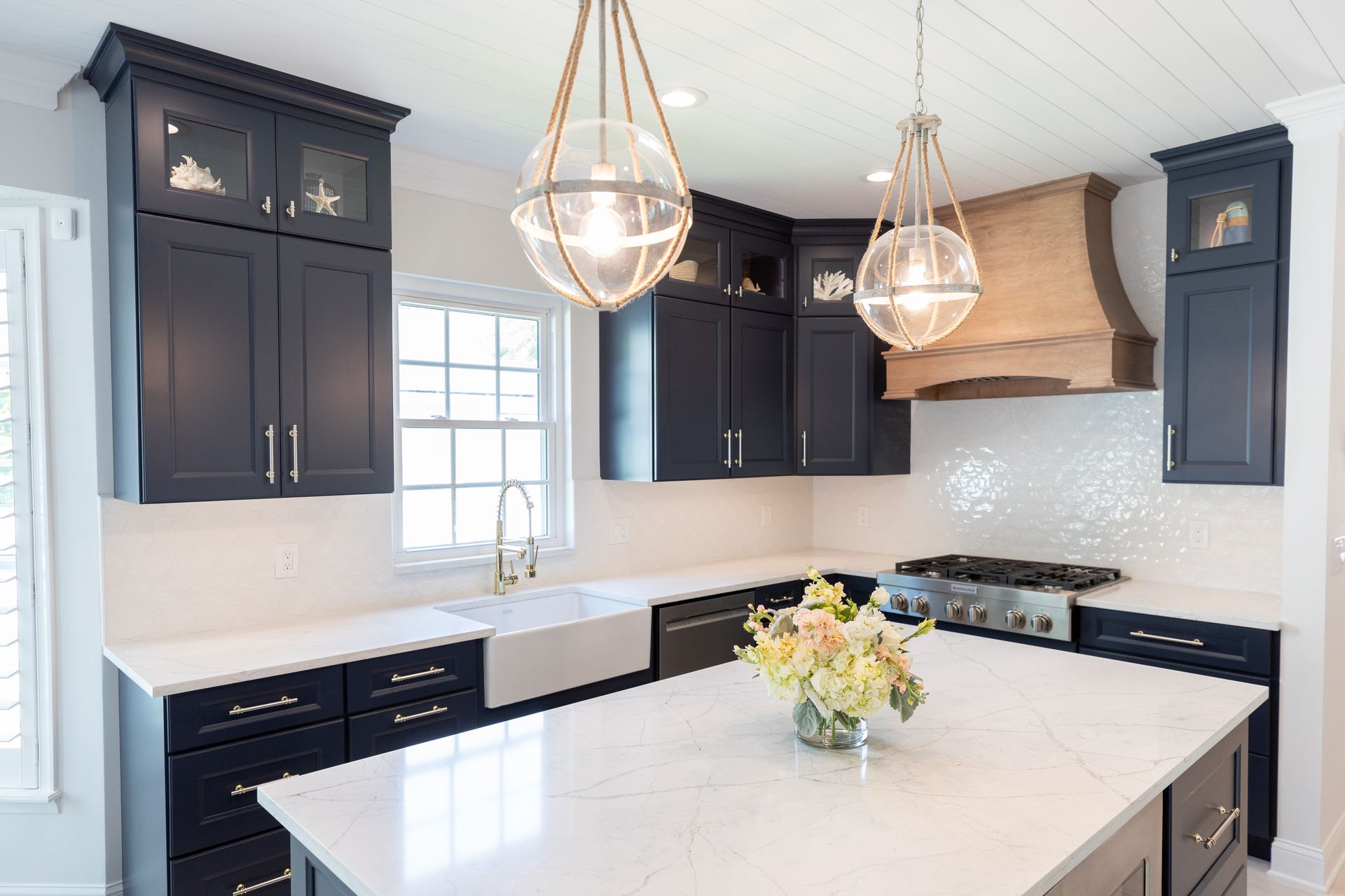A kitchen with black cabinets , white counter tops , a sink , and a large island.