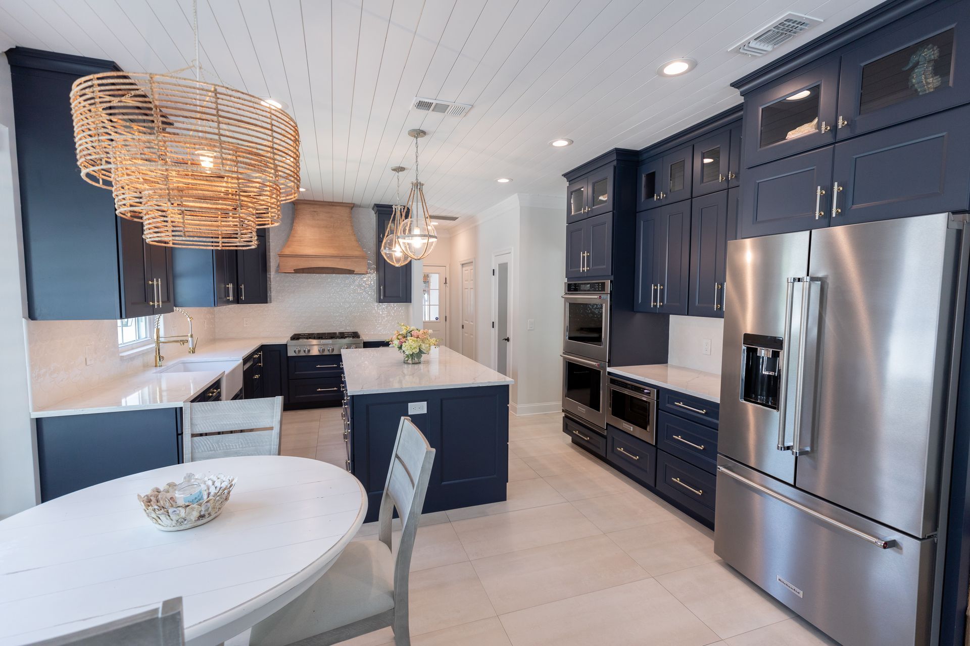 A kitchen with blue cabinets , stainless steel appliances , a table and chairs.