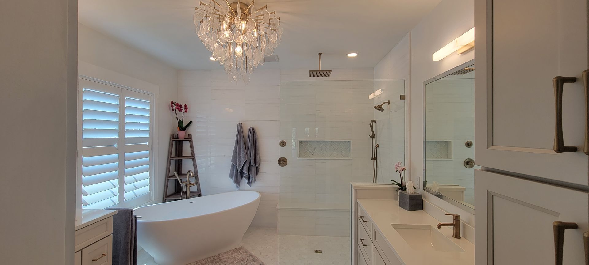 A bathroom with a bathtub , sink , mirror and chandelier.