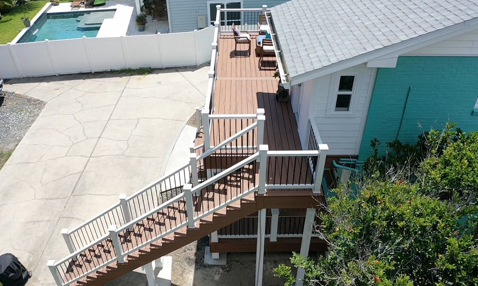 An aerial view of a house with a large deck and stairs leading up to it.