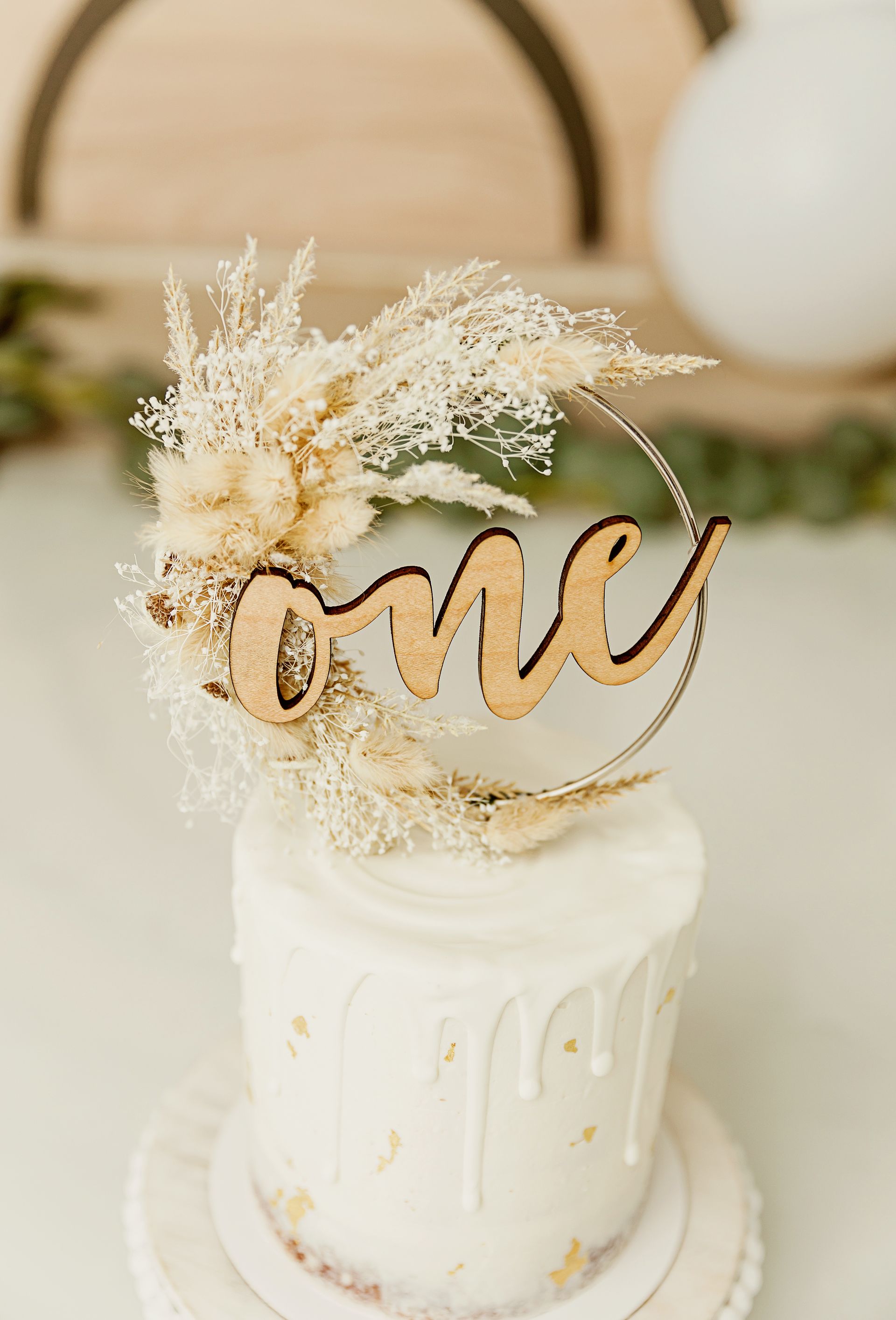 Neutral-toned cake with textured frosting and simple boho decoration for a baby’s first birthday.