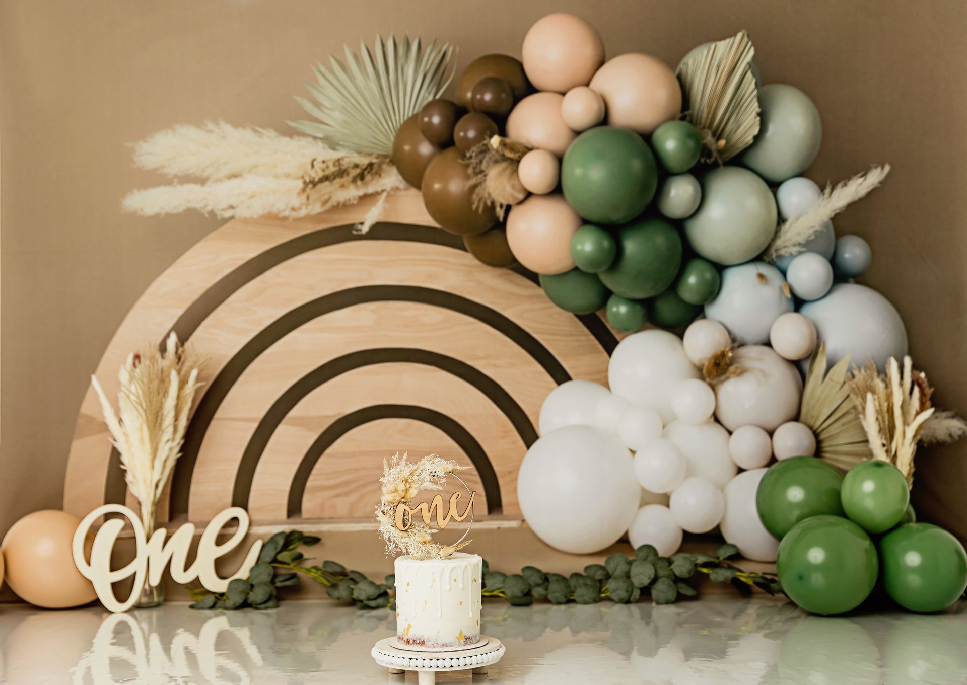 Neutral baby boy first birthday setup with earthy tones and balloon arch | Boho cake smash photography Raleigh NC Sage green and earth tones boho baby cake for first birthday photo session | Luciana Galucci Photography - Cake smash Raleigh NC
