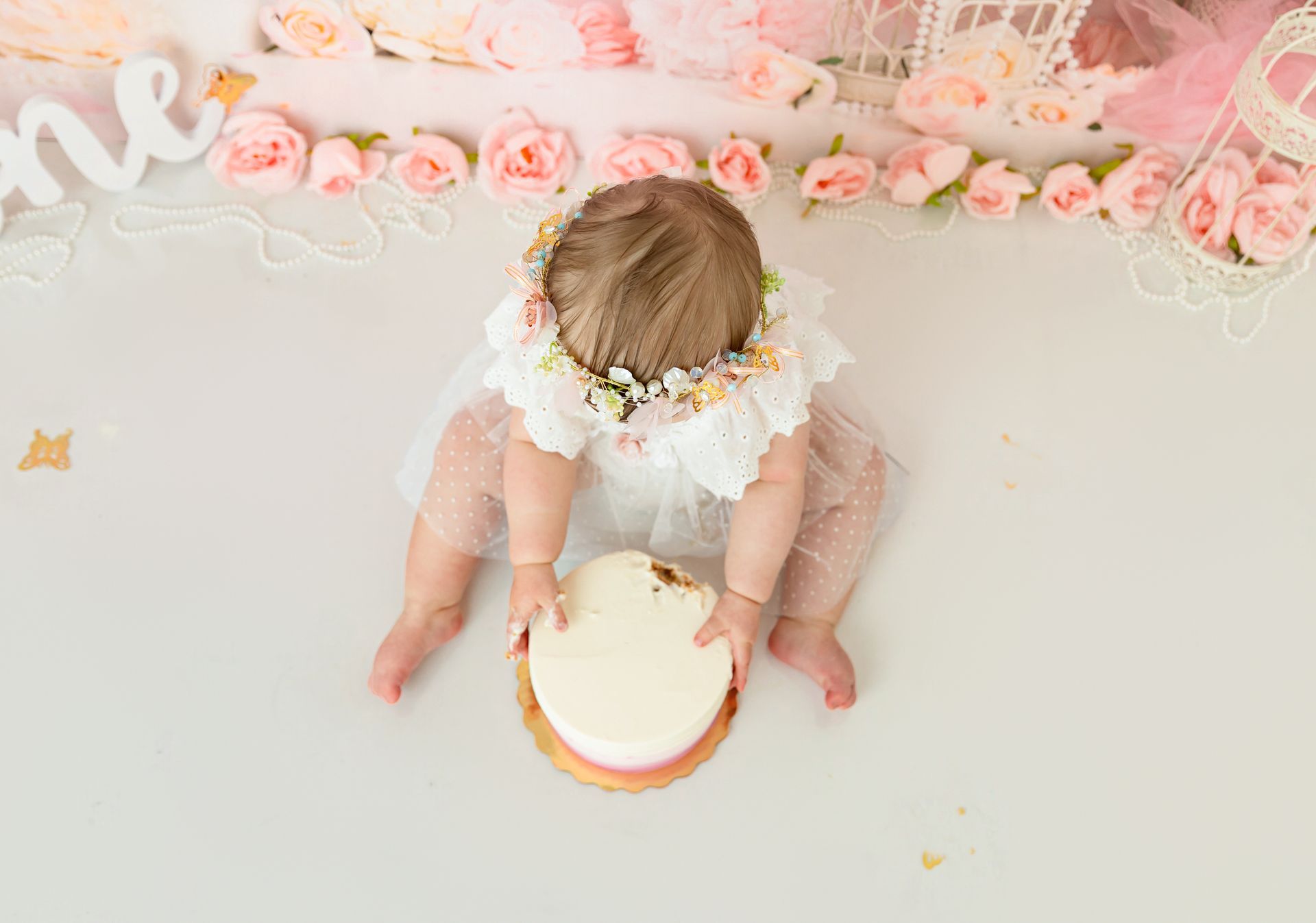 Smiling baby girl enjoying floral cake smash in Cary photography studio